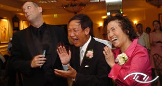 The Fun Wedding Guy, Wedding Entertainment Director® Peter Merry, eliciting laughter from the Father and Mother of the Bride at a Wedding Reception. (Photo Credit: Mike Colón Photography)