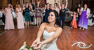 Michaela preparing to toss her Bouquet as the single ladies are gathered and waiting in the background at the Capital Plaza Hotel in Topeka, KS. Peter Merry with MERRY WEDDINGS was their Wedding Entertainment Director®. (Photo Credit: Melissa Sigler Photography)